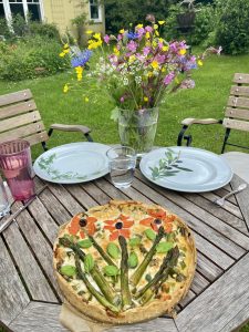 Spargelquiche auf Tisch mit Blumen